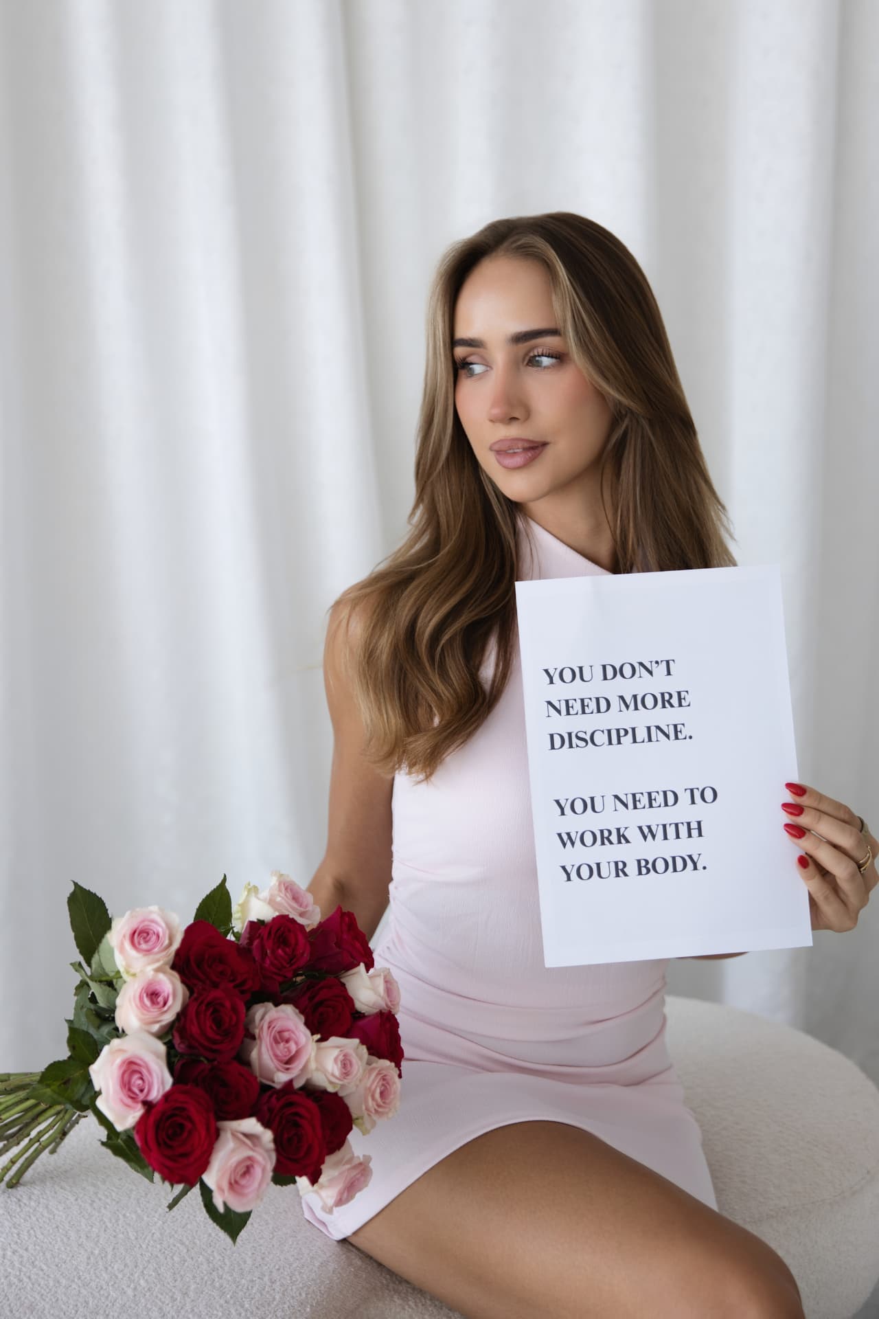 Julia holding a sign that reads 'You don't need more discipline. You need to work with your body.'